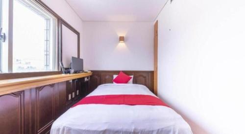 a room with a bed with a red pillow on it at Tabist Hotel Sankoen in Hitachi