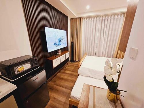 バギオにあるCondotel Near SM Baguio, Cathedral & Session Rd by Le Chateau Baguioのベッドとテレビがあるホテルの部屋