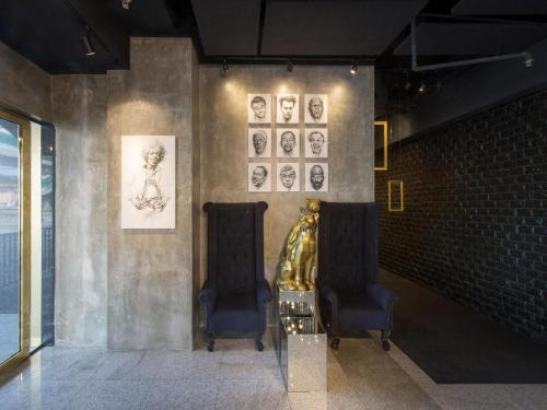 two chairs in a room with pictures on the wall at The Hulo Hotel & Gallery in Kuala Lumpur