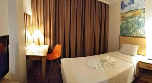 a hotel room with a bed and a desk and a bed and a chair at The Orchid Hotel in Sibu