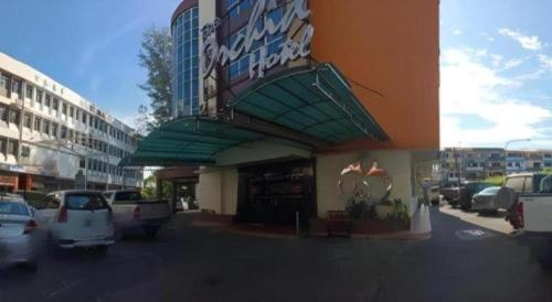 a building with cars parked in a parking lot at The Orchid Hotel in Sibu