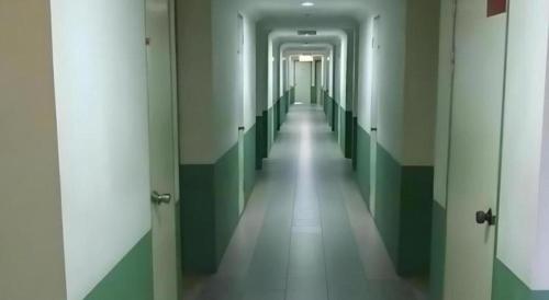 a long hallway with green and white walls and doors at Hotel Hung Hung in Kuching