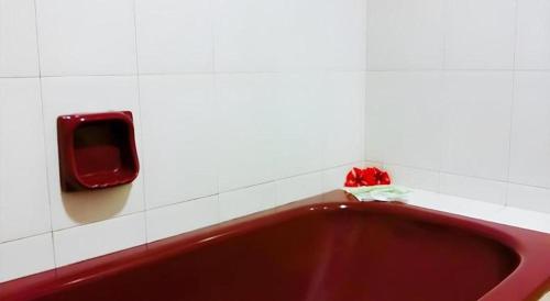 a red bath tub with a soap dispenser on a wall at Global Hotel Labuan in Labuan