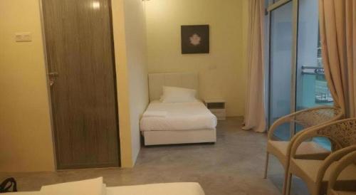 a bedroom with a bed and a chair and a window at Hotel Pangkor Mutiara in Pangkor