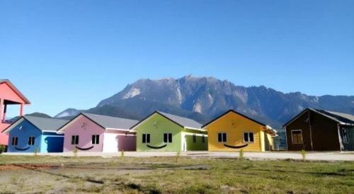 a row of colorful houses with a mountain in the background at Happy Village Kundasang in Ranau