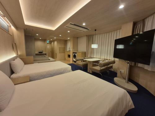 a hotel room with two beds and a flat screen tv at UH Suite Namba Station The Spa in Osaka
