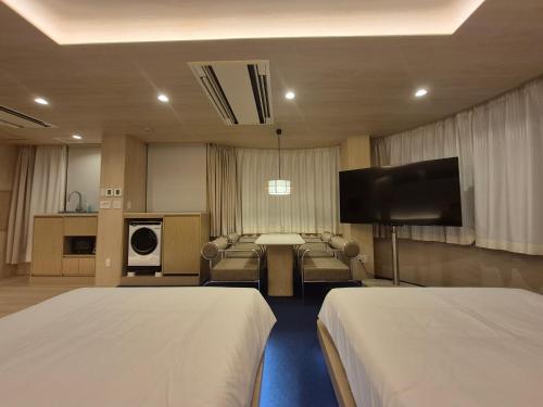 a hotel room with two beds and a flat screen tv at UH Suite Namba Station The Spa in Osaka