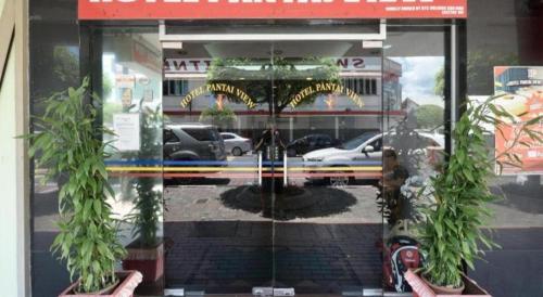 a reflection of a store front in a window with two plants at OYO 969 Hotel Pantai View in Labuan
