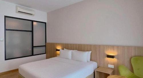 a bedroom with a white bed and a green chair at S Hotel in Johor Bahru