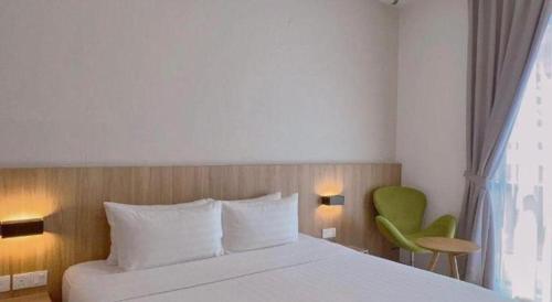 a bedroom with a bed and a green chair at S Hotel in Johor Bahru