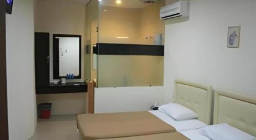 a bedroom with two beds and a mirror at Rafayeh Hotel in Seremban