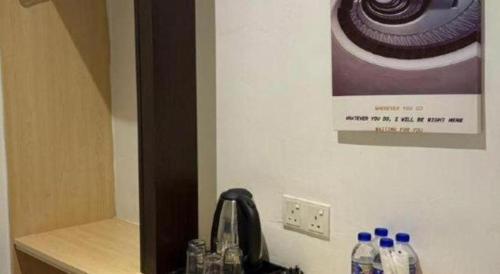 a sink with bottles of water and a picture on the wall at Hotel Zamburger Bentong in Bentong