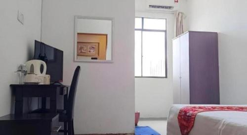 a bedroom with a bed and a desk and a window at OYO 90785 Pandan Hotel in Kota Kinabalu