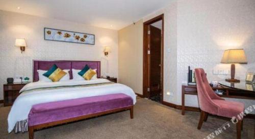 a bedroom with a large bed and a pink chair at Shunde Emperor Hotel in Shunde
