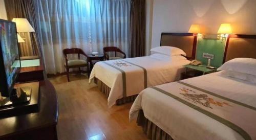 a hotel room with two beds and a flat screen tv at Quanzhou Overseas Chinese Hotel in Quanzhou
