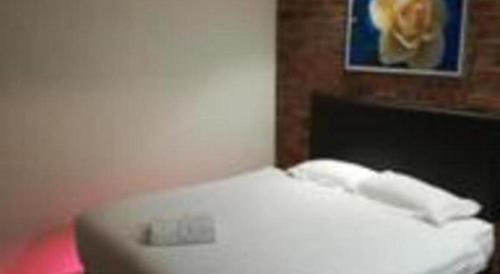 a white bed in a room with a picture at Rock & Roll Hotel Klang in Klang