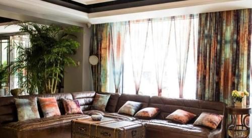 a brown leather couch in a living room with a large window at James Joyce Coffetel Xian Big Goose Pagoda Tang Paradise Branch in Xi'an