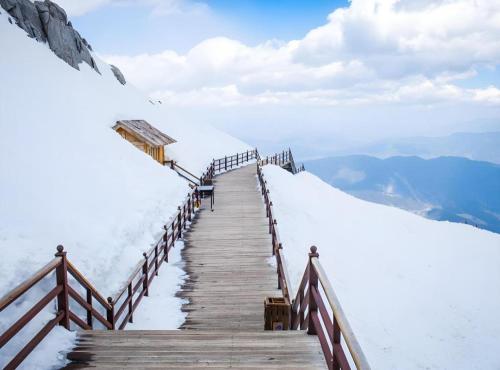 a wooden path up a mountain in the snow at James Joyce Coffetel·Lijiang Old Town Centeral in Lijiang