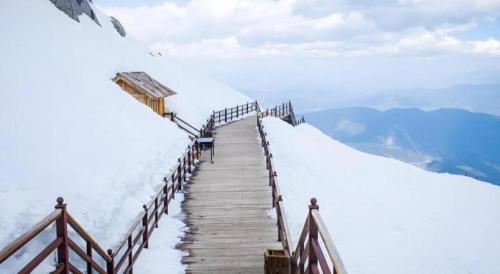 a wooden path on top of a snow covered mountain at James Joyce Coffetel·Lijiang Old Town Centeral in Lijiang