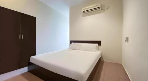 a white bed in a small room with a air conditioner at SPOT ON 91178 Motel Impian in Seri Manjung
