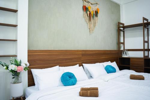 two beds in a room with white sheets and blue pillows at Villa De Doc Let Homestay in Nha Trang