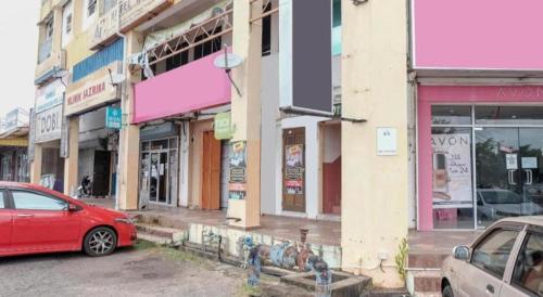 a red car parked on a street in front of buildings at OYO 90120 MI Hotel Dungun in Dungun
