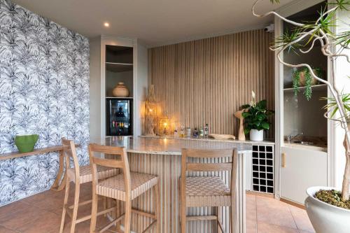 a kitchen with a bar with stools at SEASENSE Boutique Beach Villa in Wilderness