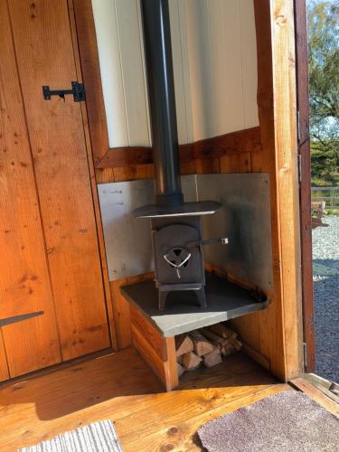 a wood fired stove in a room with a door at Berwyn Shepherds Hut in Wrexham