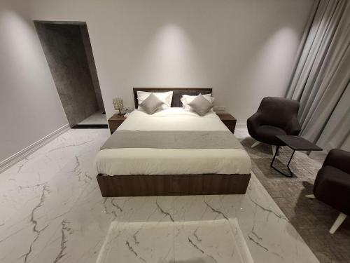 a bedroom with a bed and a chair in a room at Al Safwa One in Al Ḩadd
