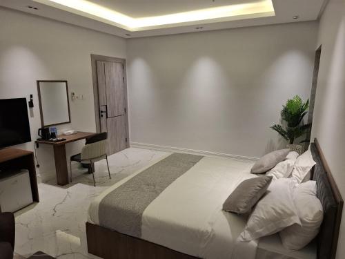 a bedroom with a bed and a desk and a television at Al Safwa One in Al Ḩadd