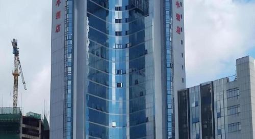a tall glass building with a crane in front of it at 7 Days Premium Zhuhai Gongbei Light Railway Branch in Zhuhai