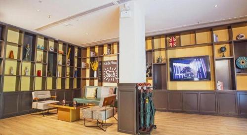 a lobby with a television and a couch and chairs at City Comfort Premier Hotel Xiaogan Anlu Railway Station Dongda Times Square in Xiaogan