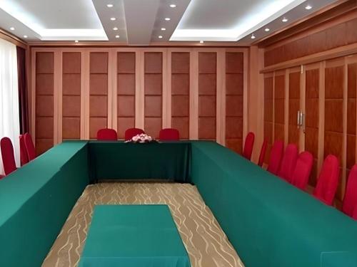 a conference room with a green table and red chairs at Kunming Dianchi Garden Hotel & Spa in Kunming
