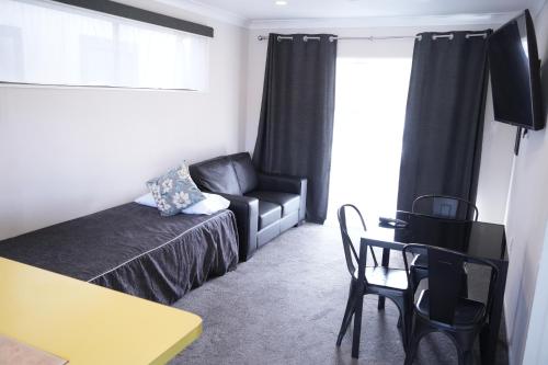 a bedroom with a couch and a chair and a table at Accommodation Gateway Motel in Palmerston North