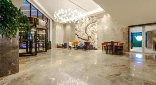 a lobby with a large room with tables and chairs at Echarm Hotel Guizhou Xingyi Jushan Avenue in Xiawutun