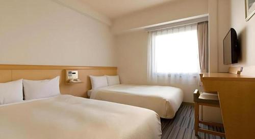 a hotel room with two beds and a window at Premier Hotel Cabin Matsumoto in Matsumoto