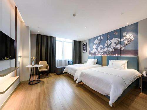 a hotel room with two beds and a table at Magnotel Hotel Dongxing Guomen Port in Fangcheng