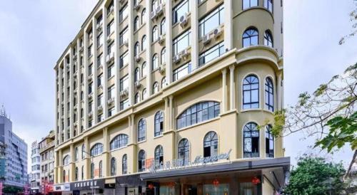 a large yellow building with many windows on a street at Magnotel Hotel Dongxing Guomen Port in Fangcheng