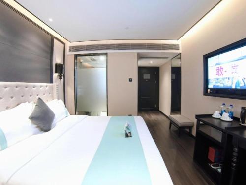a bedroom with a large white bed and a flat screen tv at Xana Hotelle Zhuhai Gongbei Port in Zhuhai