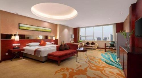 a hotel room with a bed and a living room at Ramada by Wyndham Zibo in Zibo