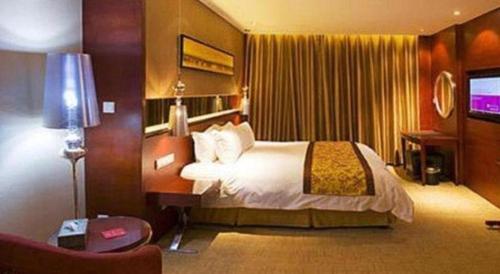 a hotel room with a bed and a television at Ramada by Wyndham Zibo in Zibo