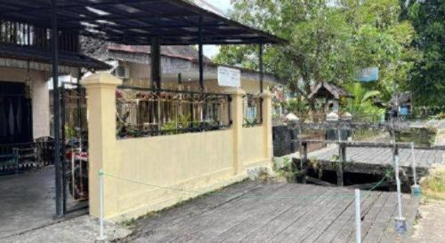 a building with a fence and a wooden deck at SPOT ON 92529 Penginapan Wisma Bintang Syariah Near MTs Al Ma'arif Kota Bangun in Derawan Islands