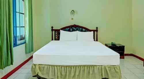 a bedroom with a large white bed in a room at Hotel O Tri Homestay in Palangkaraya