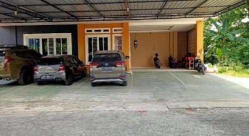 two cars parked in a parking lot in front of a building at Hotel O Tri Homestay in Palangkaraya