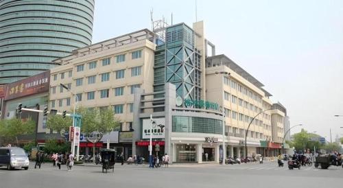 un grande edificio su una strada cittadina con persone di fronte di GreenTree Inn Changshu South HaiYu Road Pedestrian Street Business Hotel a Suzhou