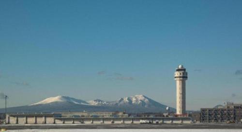 a lighthouse with mountains in the background at Air Terminal Hotel in Chitose