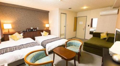 a hotel room with two beds and a couch at Hotel Areaone Miyazaki in Miyazaki
