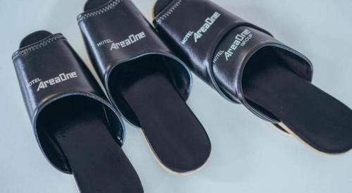 a pair of black slippers sitting on a table at Hotel Areaone Miyazaki in Miyazaki