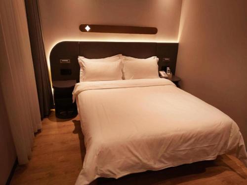 a bed with white sheets and pillows in a room at GreenTree Inn Datong YundinGYAyuan Express Hotel in Datong