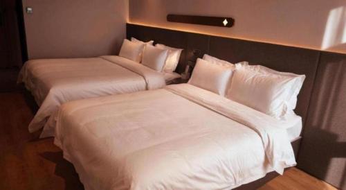 two beds in a hotel room with white sheets and pillows at GreenTree Inn Datong YundinGYAyuan Express Hotel in Datong